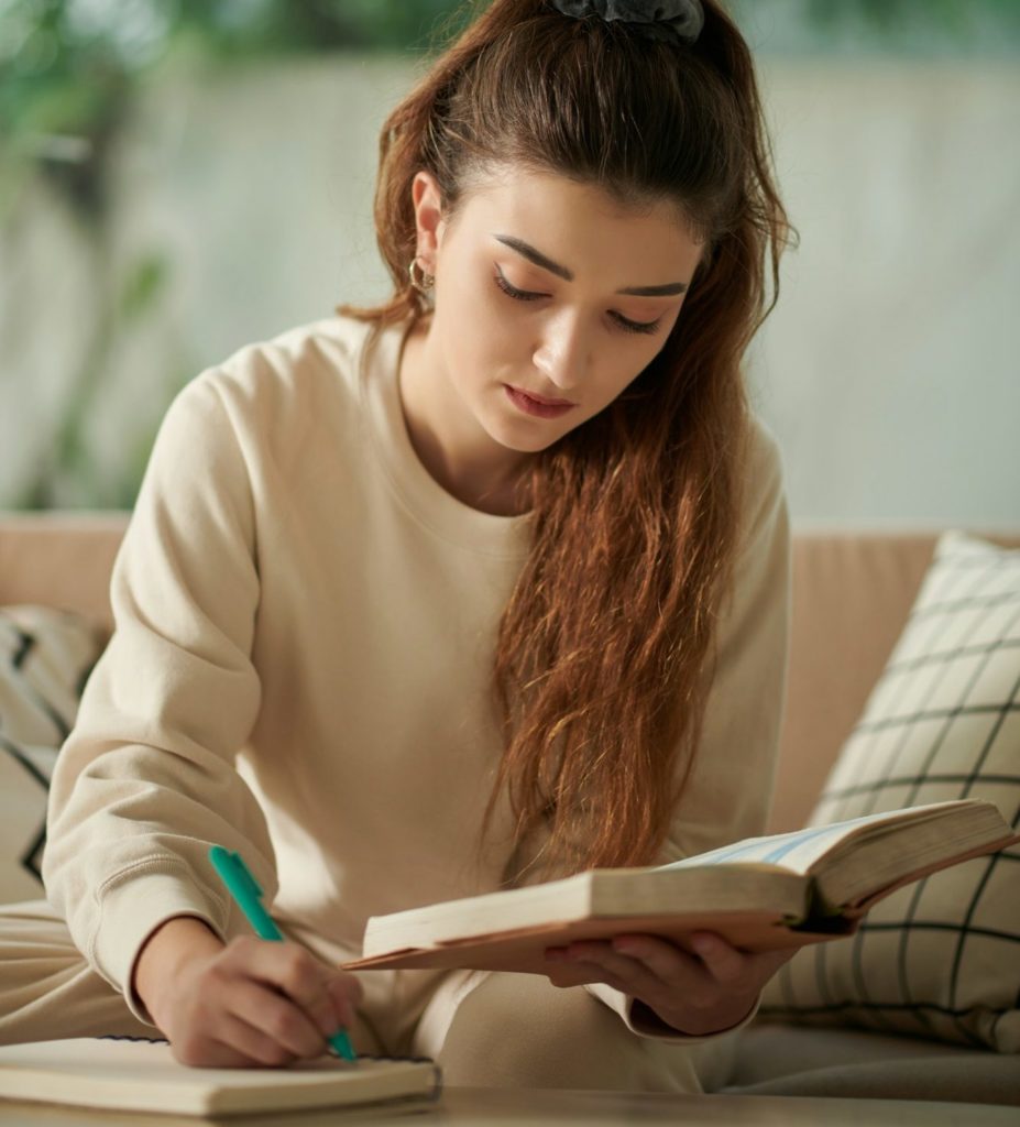 Persona estudiant amb un llibre i prenent apunts